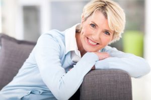 Happy middle aged woman sitting on couch